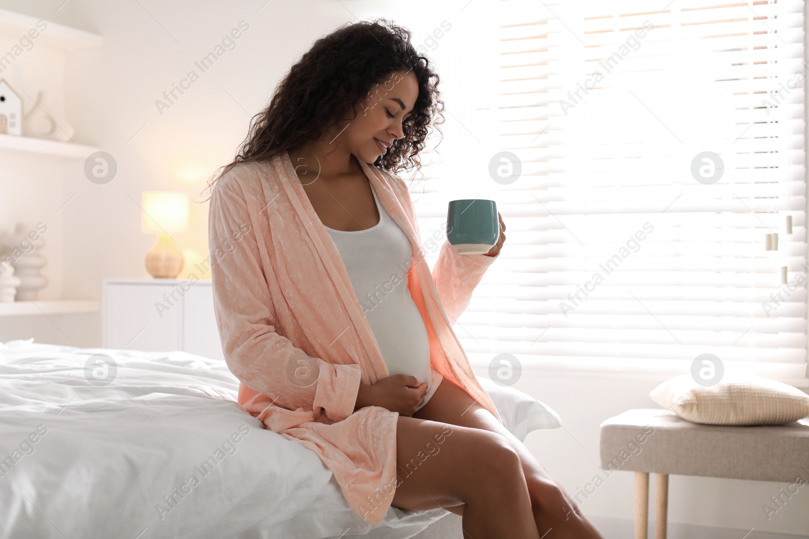 Photo of Portrait of beautiful pregnant with cup of drink on bed at home