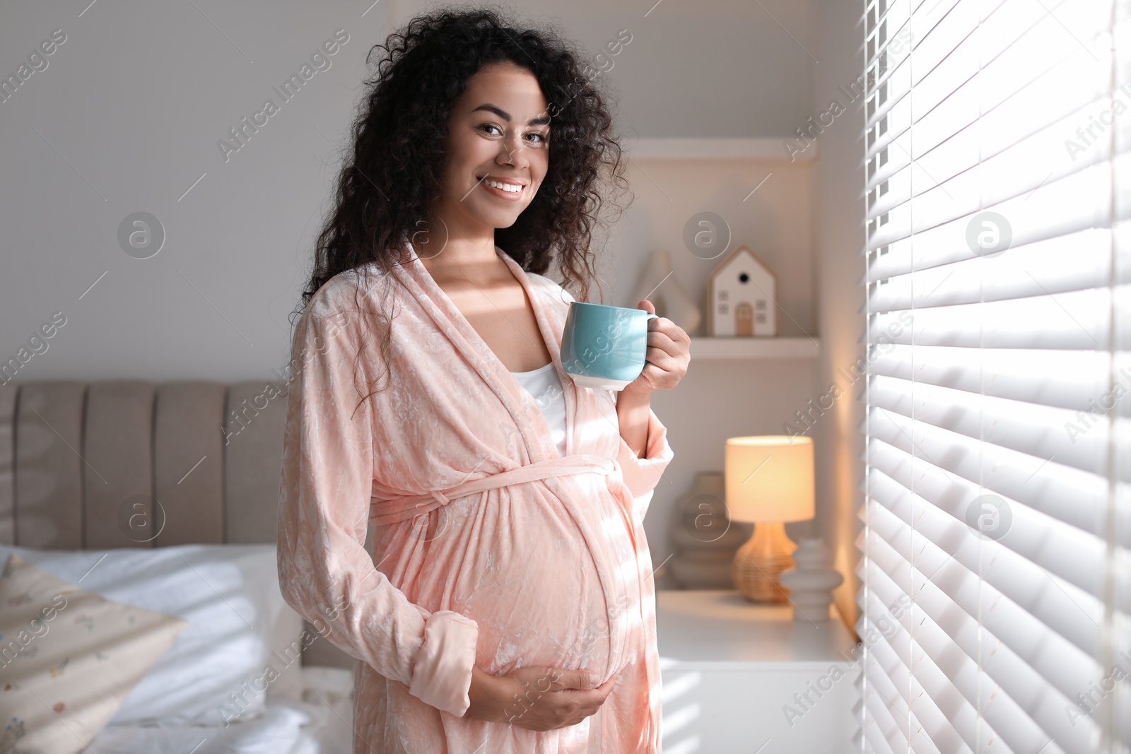 Photo of Portrait of beautiful pregnant with cup of drink near window at home