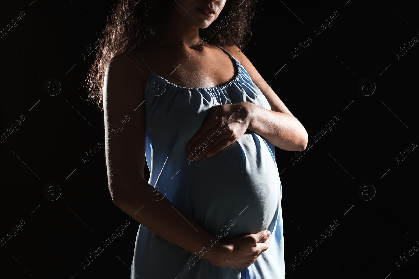 Photo of Pregnant woman on black background, closeup view