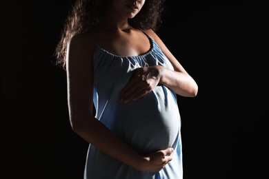 Photo of Pregnant woman on black background, closeup view