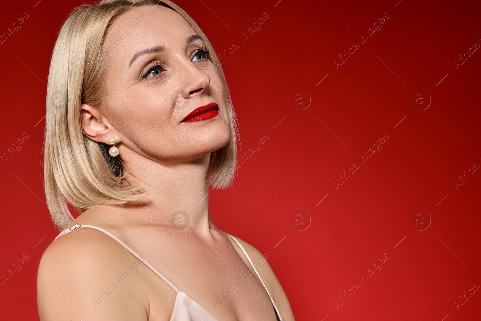 Photo of Woman with perfect makeup on red background. Space for text