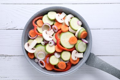 Photo of Frying pan with mix of fresh vegetables and mushrooms on white wooden table, top view