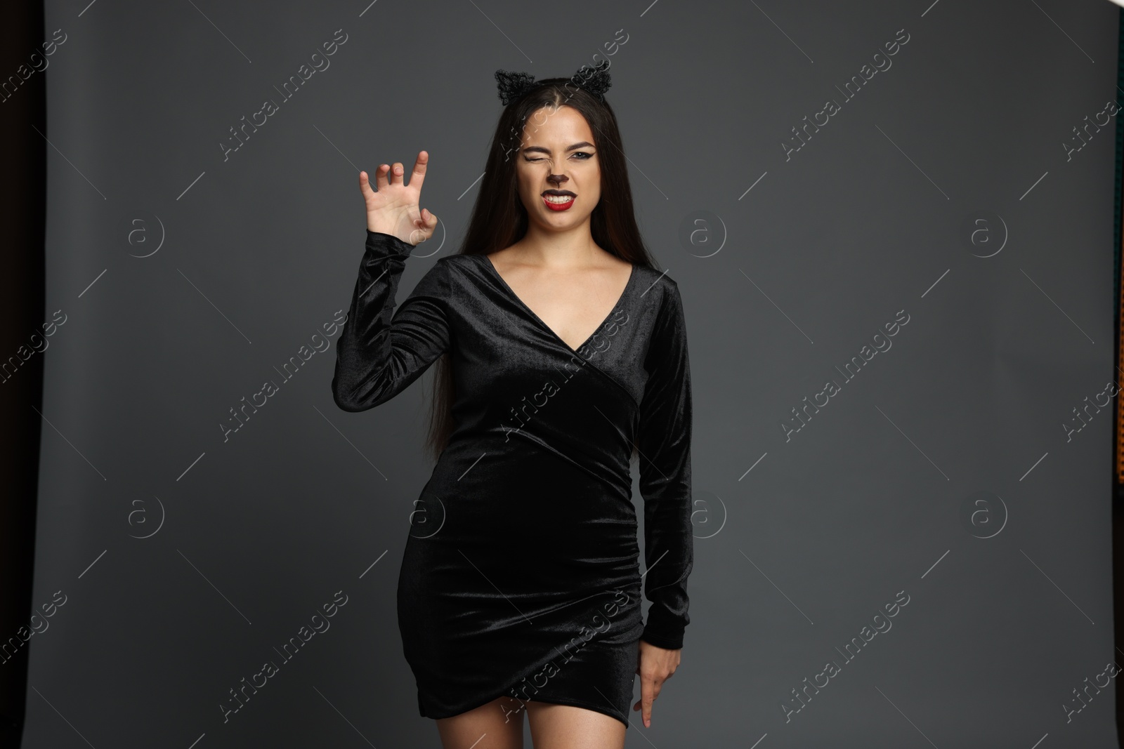 Photo of Attractive woman with cat makeup and ears on grey background