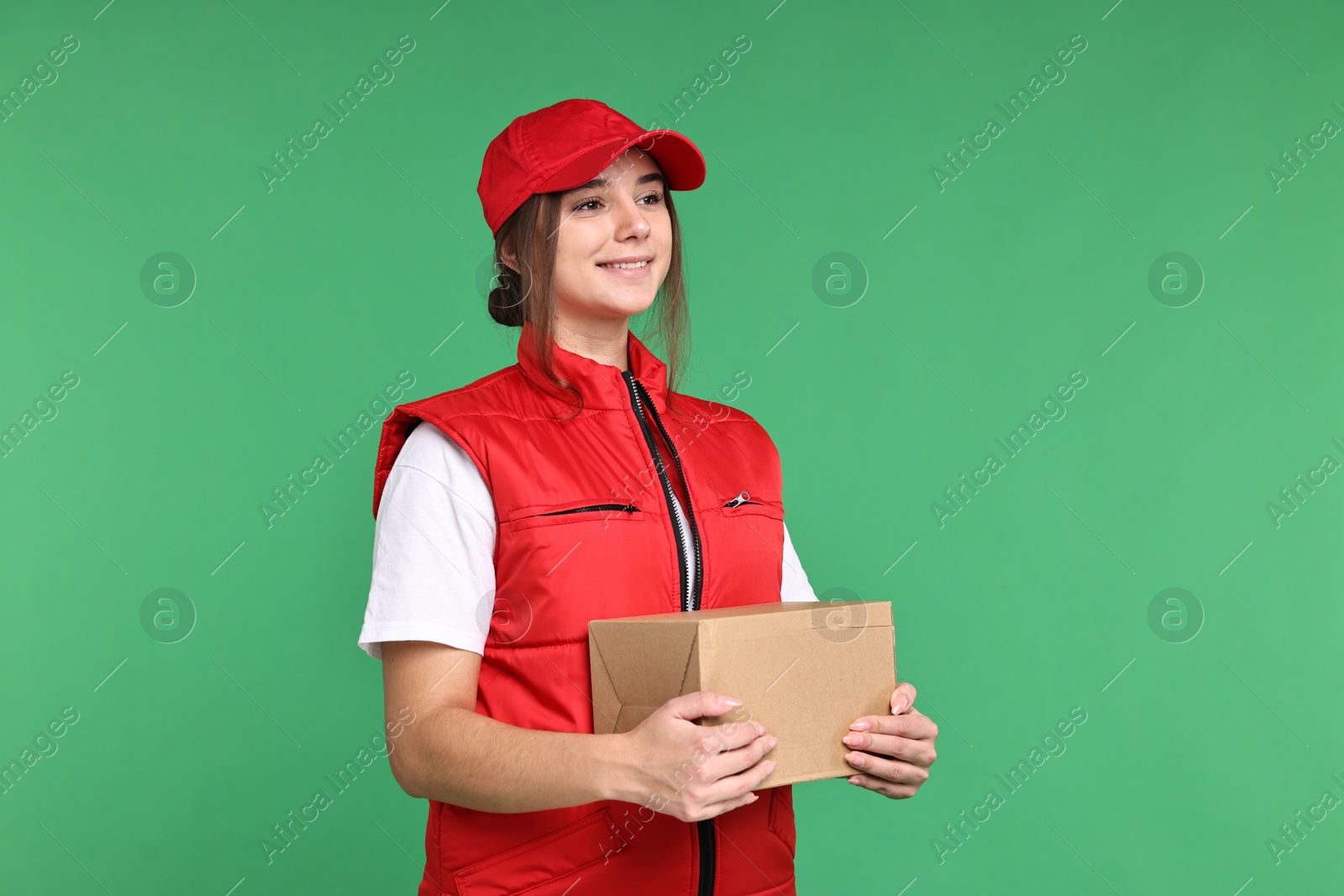 Photo of Girl in uniform with parcel on green background. Work for teenagers