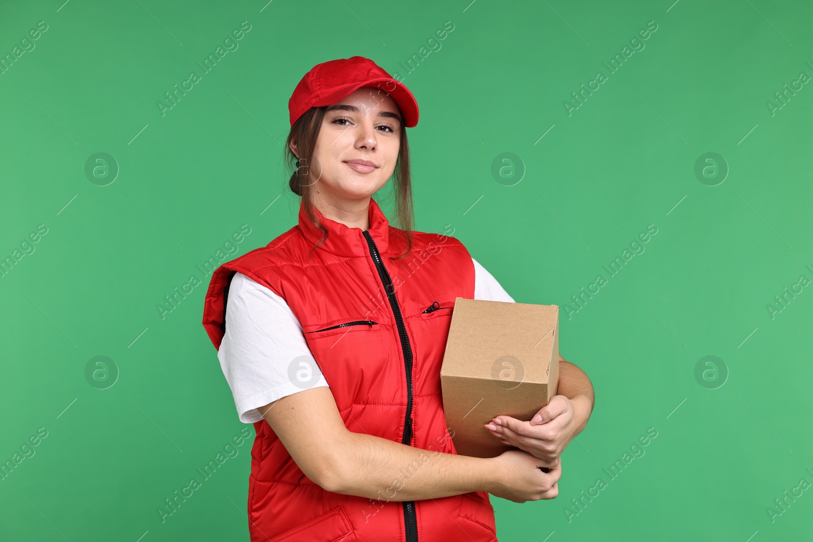 Photo of Girl in uniform with parcel on green background. Work for teenagers