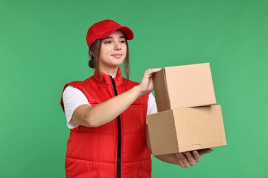 Photo of Girl in uniform with parcels on green background. Work for teenagers