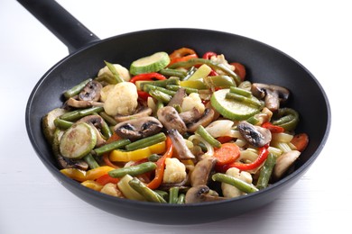 Photo of Different vegetables and mushrooms in frying pan on white table, closeup