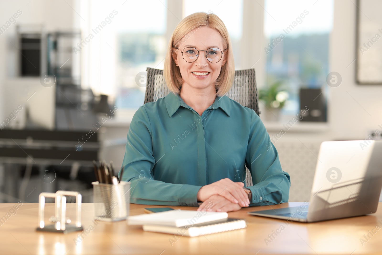 Photo of Portrait of smiling middle aged woman at table in office