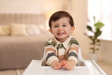 Photo of Cute little kid sitting in high chair at home