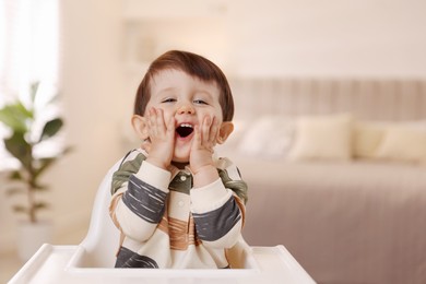 Photo of Cute little kid sitting in high chair at home