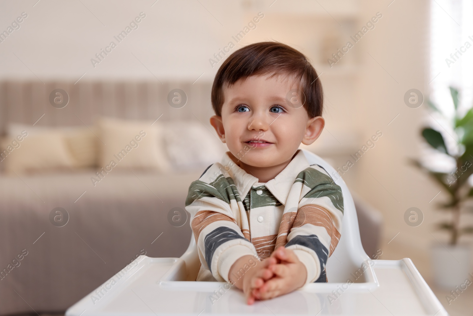 Photo of Cute little kid sitting in high chair at home