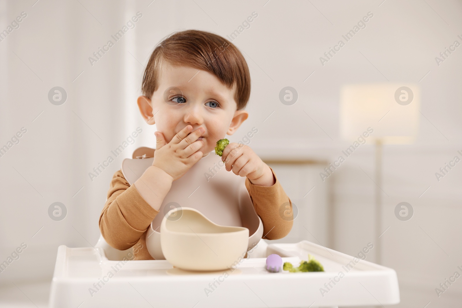 Photo of Cute little baby eating healthy food from bowl in high chair at home, space for text