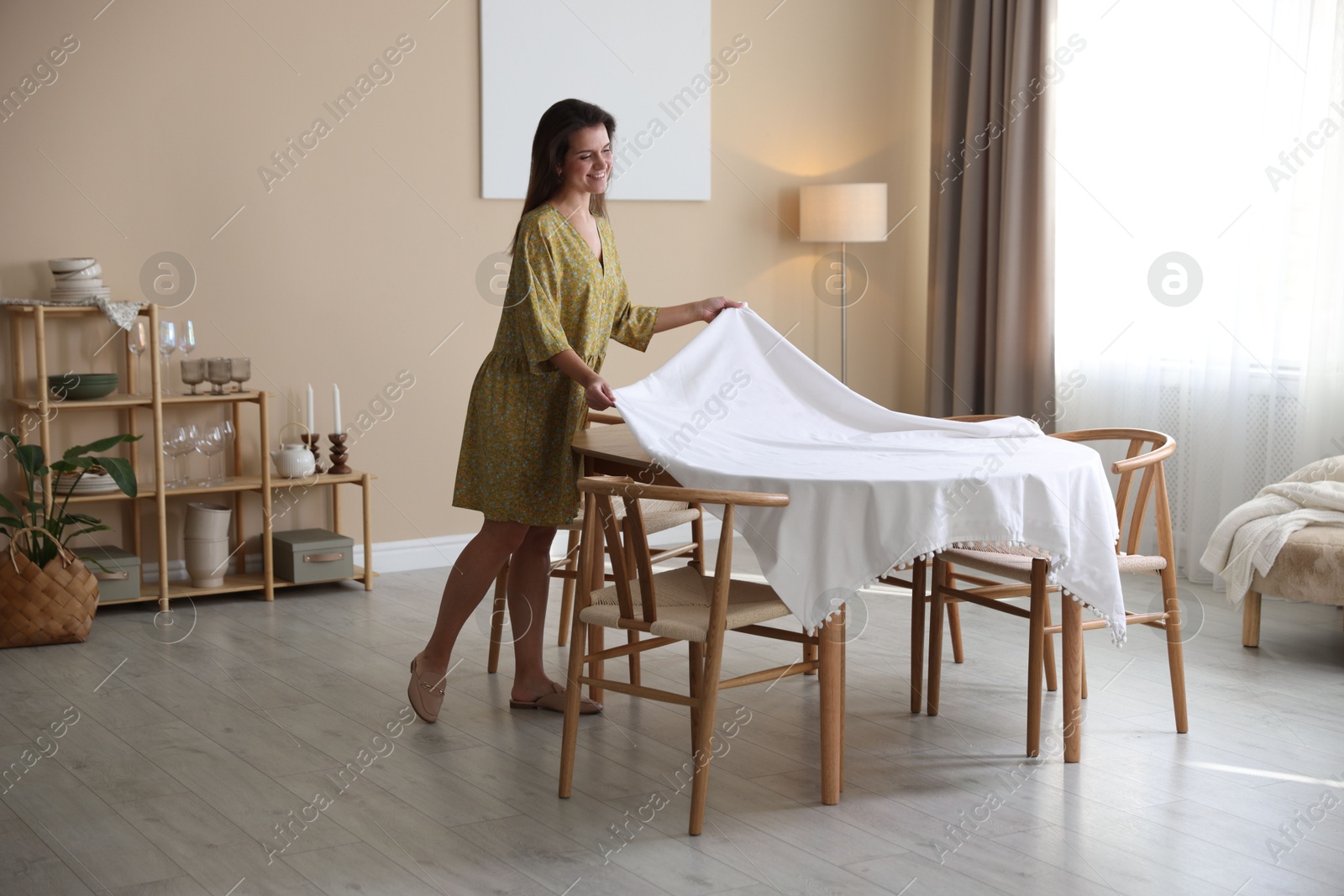 Photo of Woman laying tablecloth on table at home