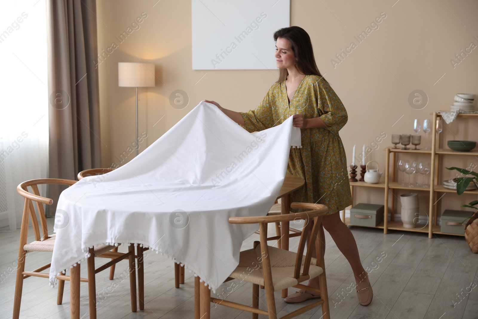 Photo of Woman laying tablecloth on table at home