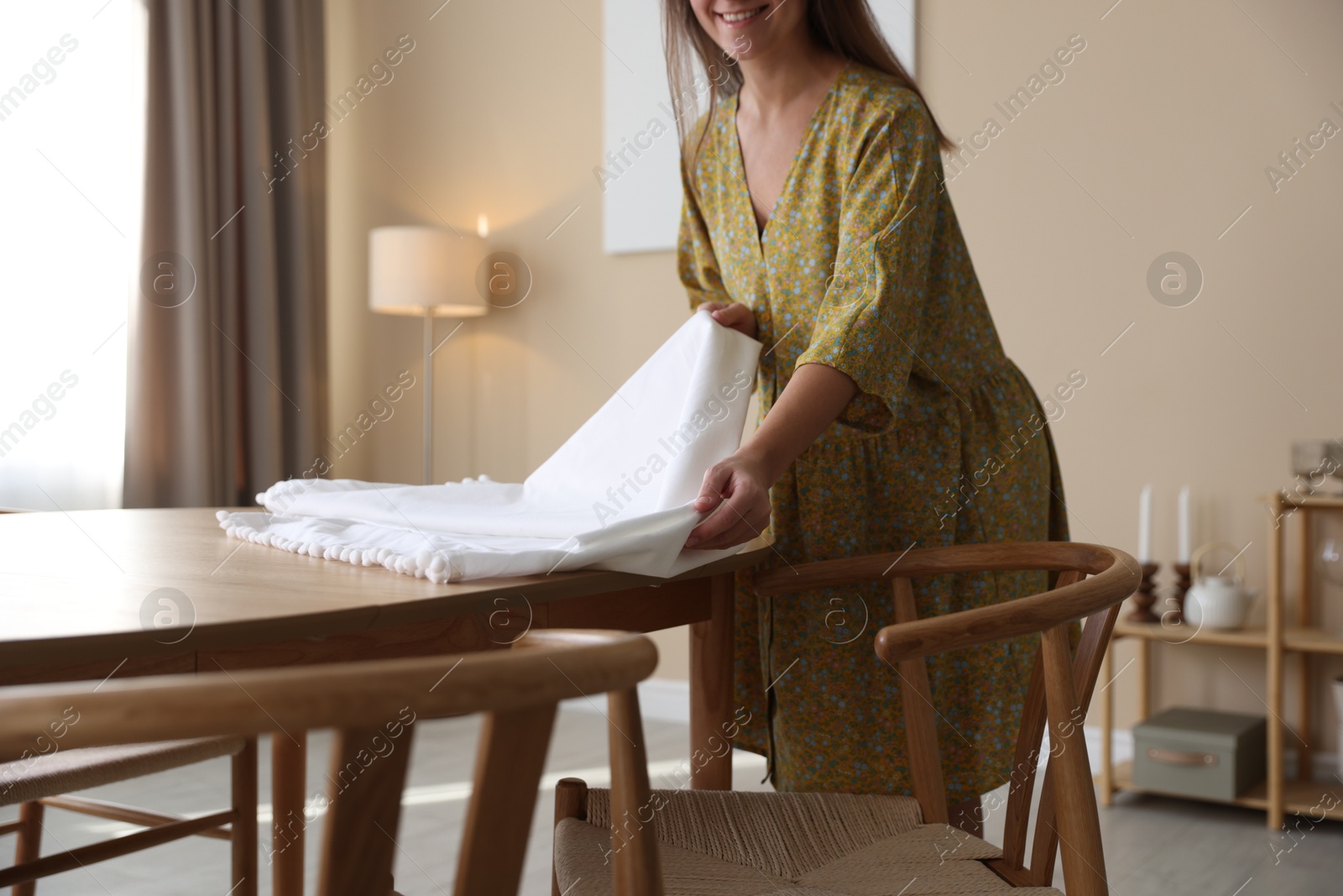 Photo of Woman laying tablecloth on table at home, closeup