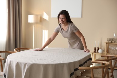 Photo of Woman laying tablecloth on table at home