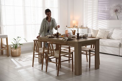 Photo of Woman setting table for dinner at home