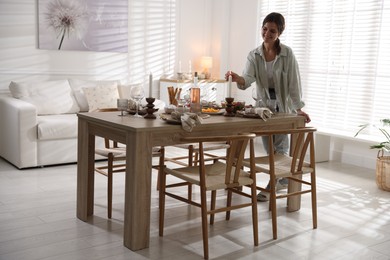 Photo of Woman setting table for dinner at home