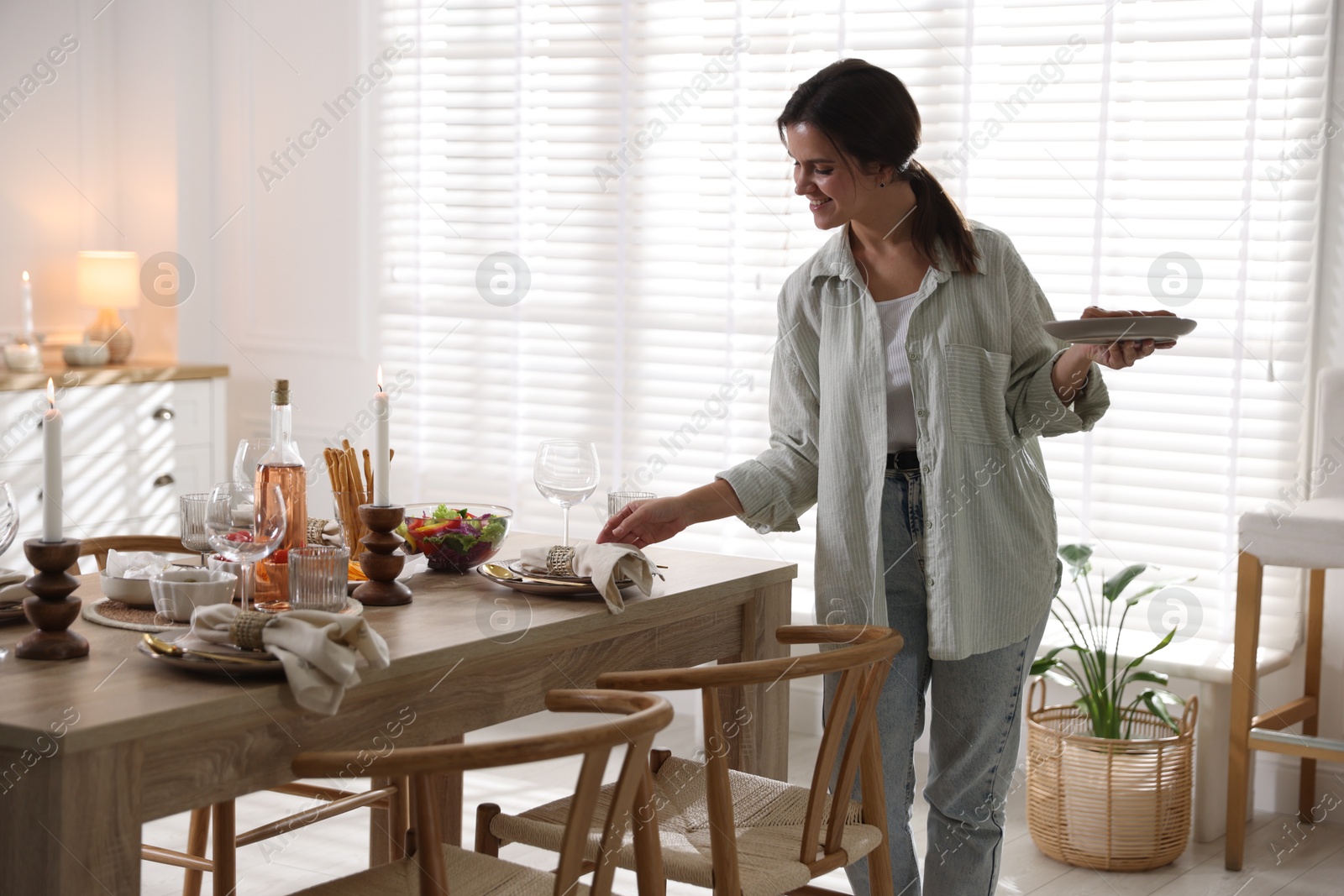 Photo of Woman setting table for dinner at home