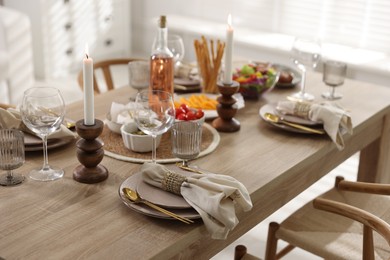 Photo of Stylish table setting with dishware, cutlery and burning candles indoors