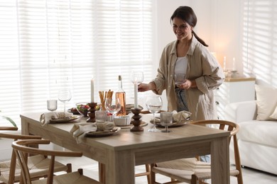 Woman setting table for dinner at home