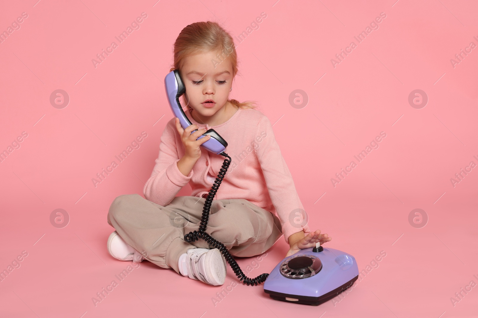 Photo of Cute little girl with telephone on pink background