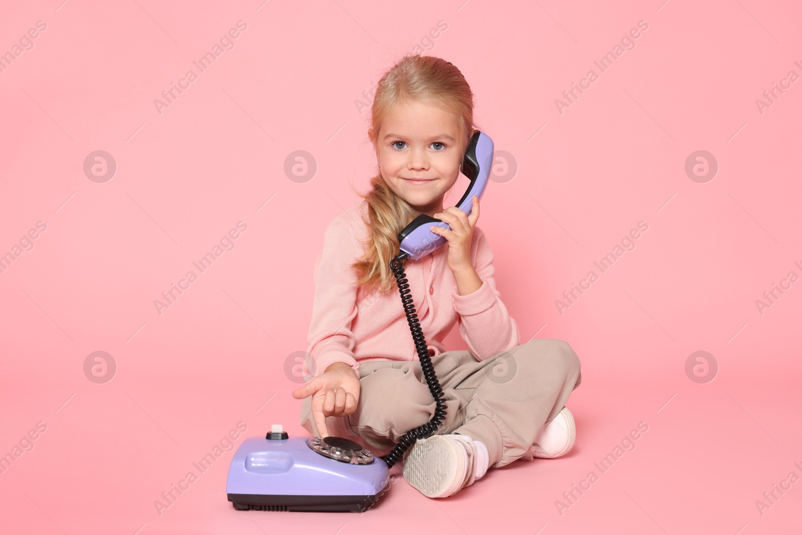 Photo of Cute little girl with telephone on pink background