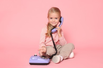 Cute little girl with telephone on pink background