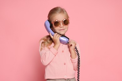 Photo of Cute little girl with handset of telephone on pink background