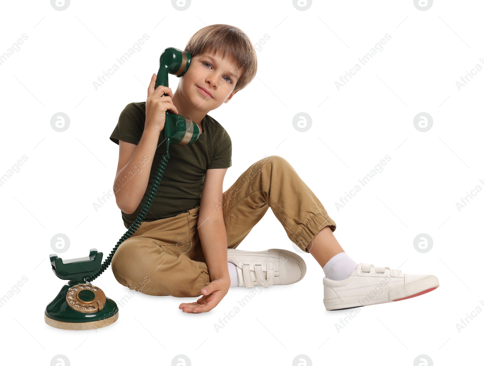 Photo of Cute little boy with vintage telephone on white background