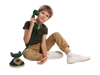 Photo of Cute little boy with vintage telephone on white background