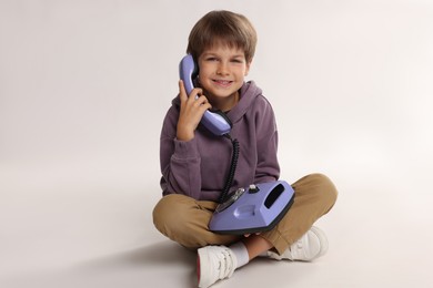 Photo of Cute little boy with old telephone on white background