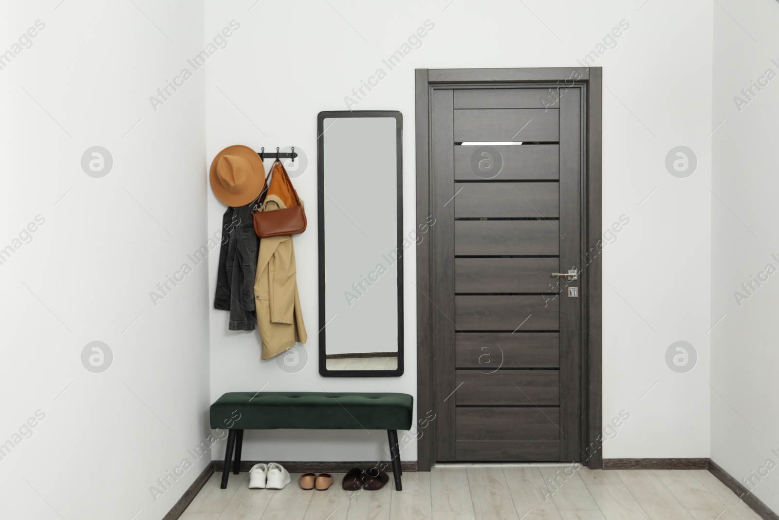 Photo of Mirror, rack with clothes and bench in hallway. Interior design