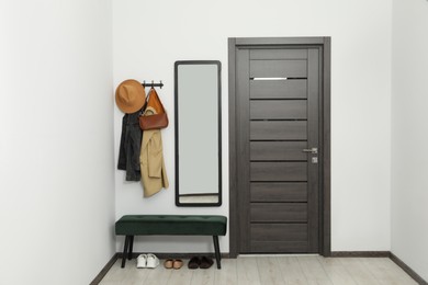 Mirror, rack with clothes and bench in hallway. Interior design