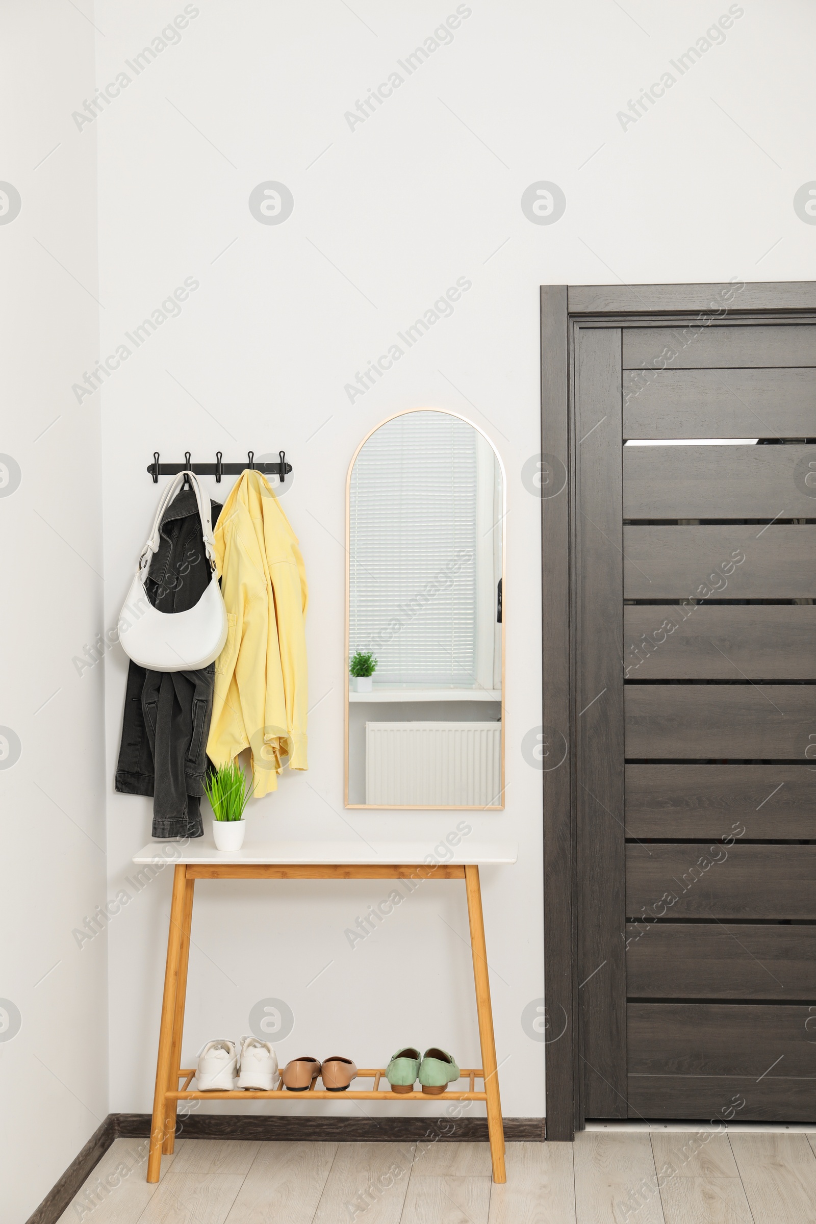 Photo of Mirror, rack with clothes and shoe storage bench in hallway. Interior design