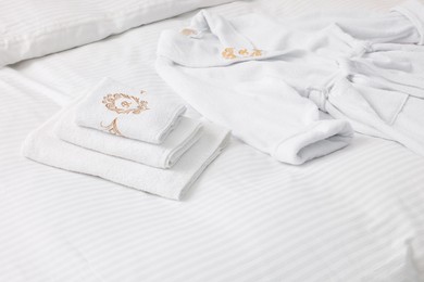 Photo of Bed with clean linens, towels and bathrobe indoors