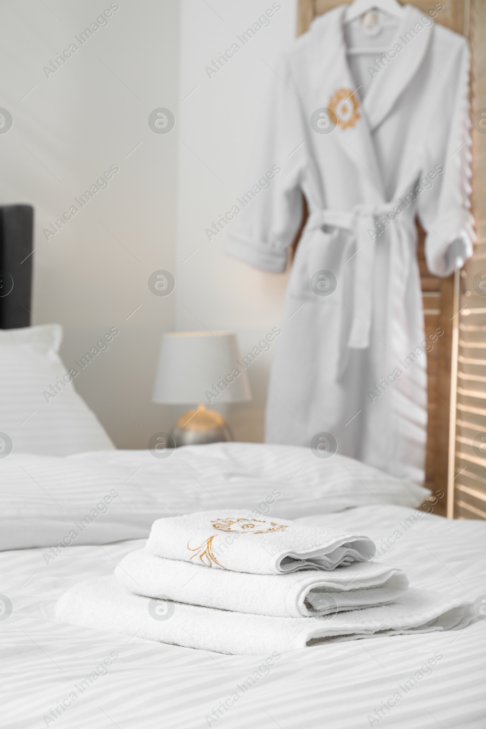 Photo of Bed with clean linens, pillow, towels and bathrobe indoors