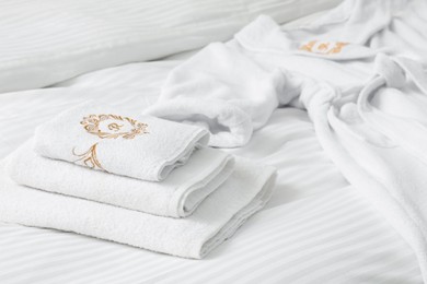 Photo of Comfortable bed with clean linens, towels and bathrobe indoors