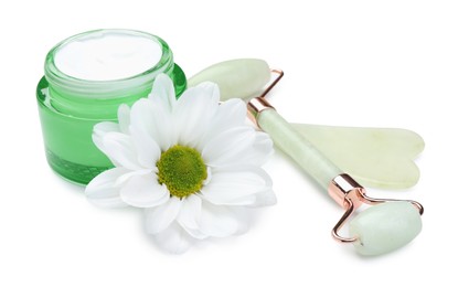 Face roller, cream, gua sha and flower isolated on white