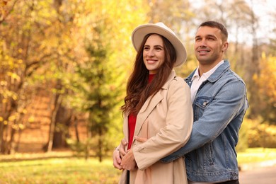 Photo of Happy couple spending time together in autumn park, space for text