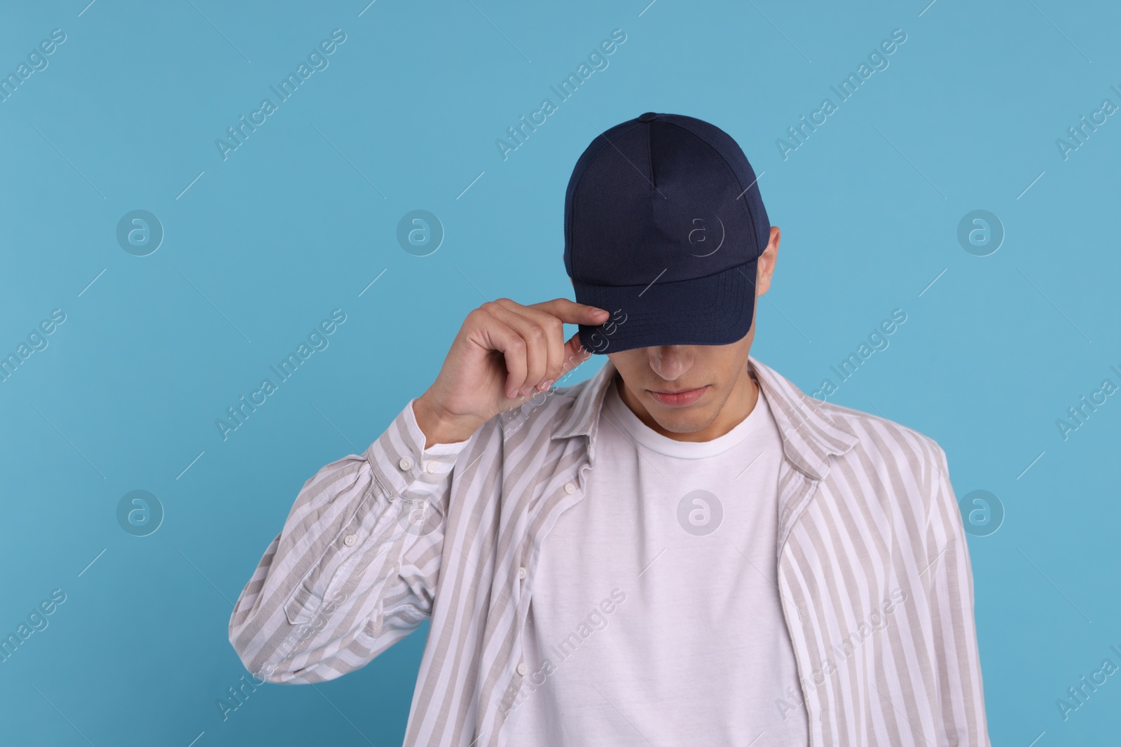 Photo of Man in stylish baseball cap on light blue background. Mockup for design