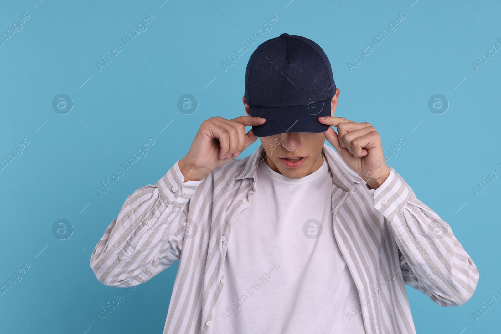 Photo of Man in stylish baseball cap on light blue background. Mockup for design