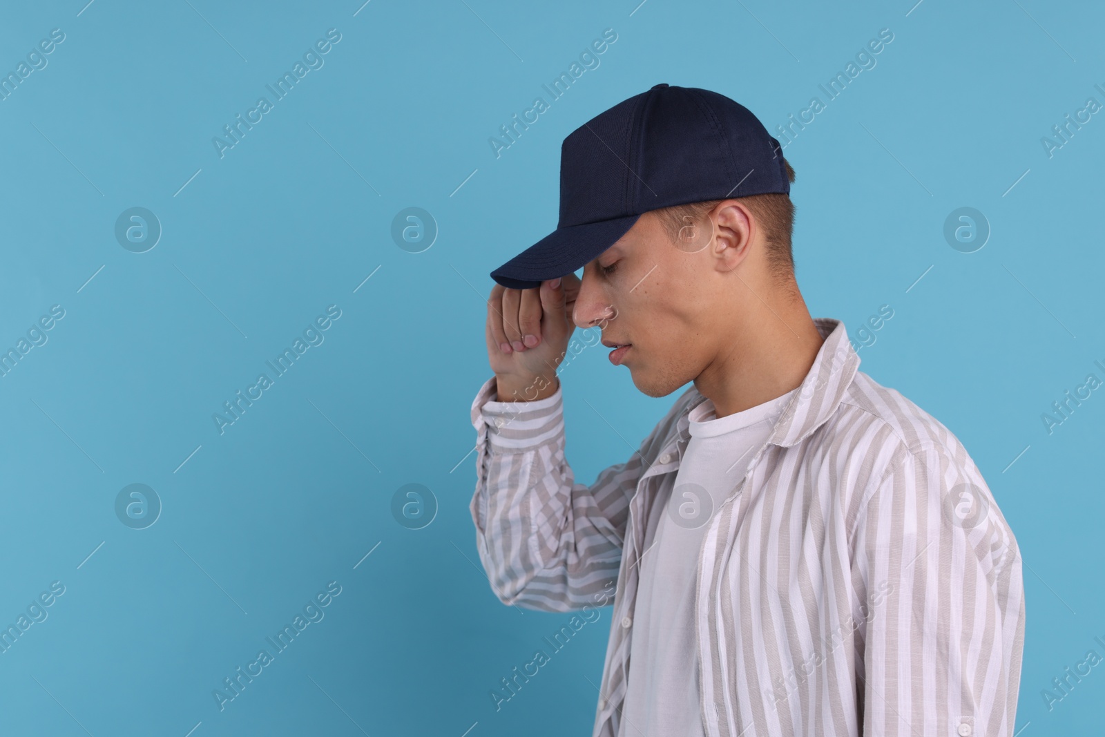 Photo of Man in stylish baseball cap on light blue background. Mockup for design