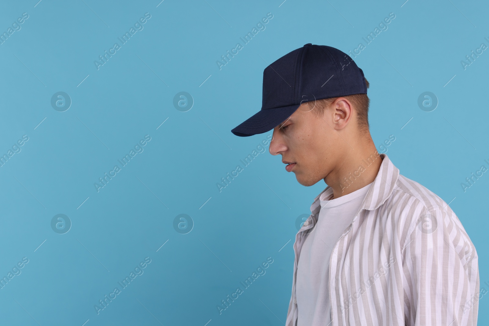 Photo of Man in stylish baseball cap on light blue background. Mockup for design