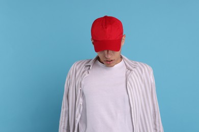 Photo of Man in stylish baseball cap on light blue background. Mockup for design