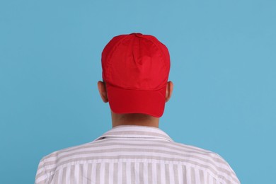 Photo of Man in stylish baseball cap on light blue background, back view. Mockup for design