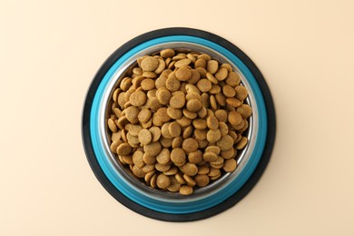 Photo of Dry pet food in feeding bowl on beige background, top view