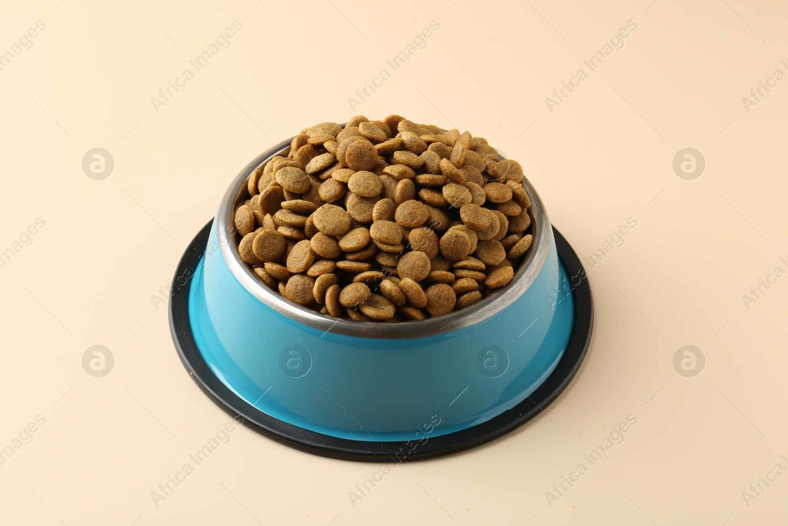 Photo of Dry pet food in feeding bowl on beige background