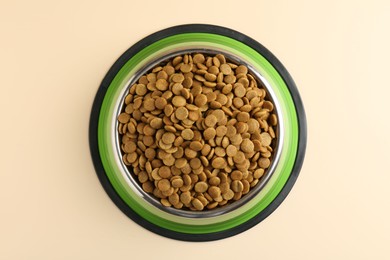 Photo of Dry pet food in feeding bowl on beige background, top view