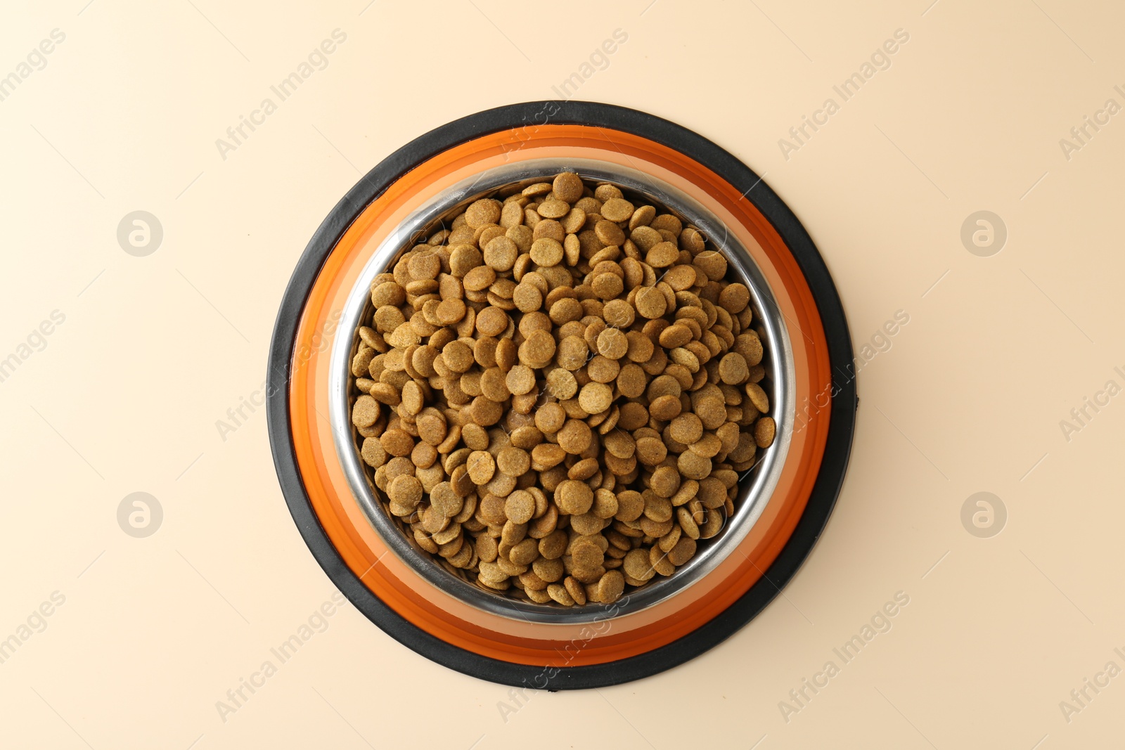 Photo of Dry pet food in feeding bowl on beige background, top view